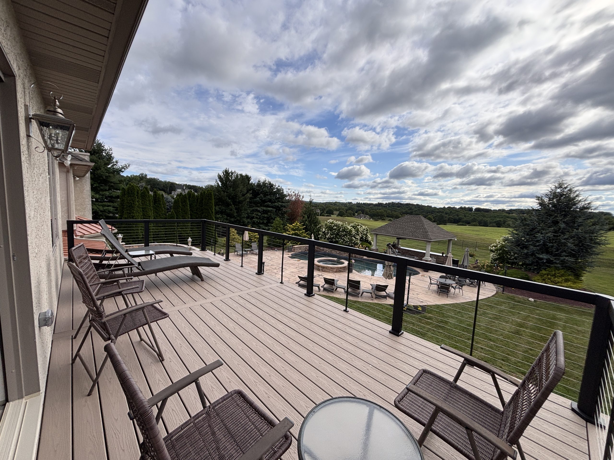 Custom outdoor living space with deck, railing, and pool area view